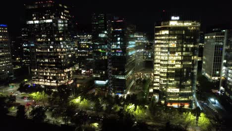 Aerial-view-circling-illuminated-high-rise-in-front-of-the-Araucano-Park,-in-Santiago-de-Chile