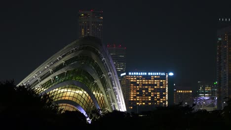 Toma-Estática-Que-Captura-La-Arquitectura-De-La-Cúpula-Iluminada-De-Los-Jardines-Junto-A-La-Bahía-Por-La-Noche,-Vistas-Desde-La-Presa-Del-Puerto-Deportivo