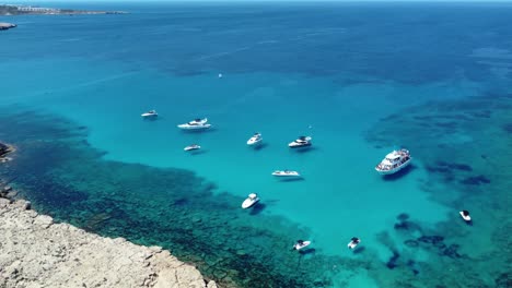 Orbit-View-over-Anchored-Boats-in-Cape-Greco-and-Blue-Lagon,-Ayia-Napa,-Cyprus