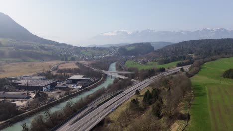 Aerial-view-of-Cars-driving-on-Highway-with-River-and-Mountains-next-to-it