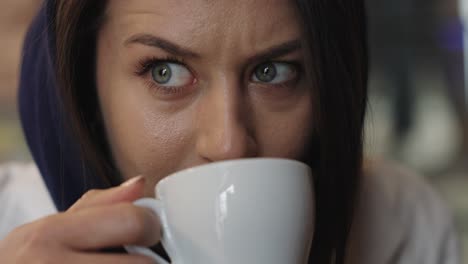 Aufgeregte-Frau-Bewegt-Die-Augenbrauen-Und-Macht-Lustige-Gesichtsausdrücke,-Während-Sie-Kaffee-Trinkt