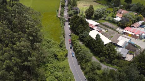 From-above,-the-tranquil-elegance-of-cars-gliding-through-sunlit-roads-embraced-by-verdant-greenery,-a-captivating-drone-view-of-nature-in-motion