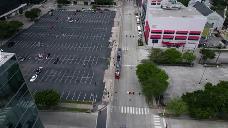 Aerial-view-following-a-MetroRail-train-moving-through-the-downtown-of-Houston,-USA