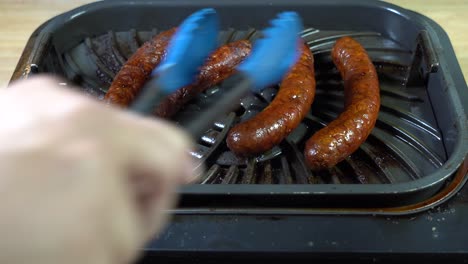 Turning-sausages-while-cooking-on-an-indoor-grill