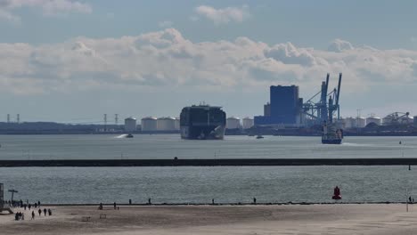 Gente-Caminando-En-La-Playa-De-Hoek-Van-Holland-Con-Vistas-Al-Puerto-Industrial-En-Holanda