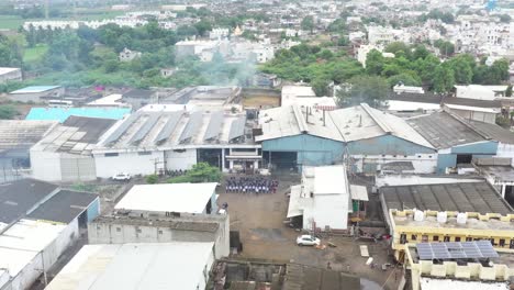 aerial-drone-view-Drone-camera-moving-upwards-showing-several-factories-and-a-lower-outlet-showing-output-workers-and-their-staff