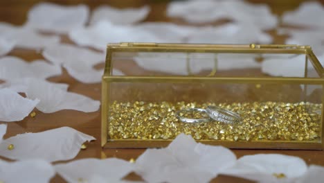 Viaje-De-Una-Caja-De-Anillo-De-Boda,-Con-Pétalos-Blancos-Y-Granos-De-Oro