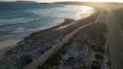 Cyclist-pedaling-on-cycle-path-along-Salmon-Beach-at-sunset,-Esperance-in-Western-Australia