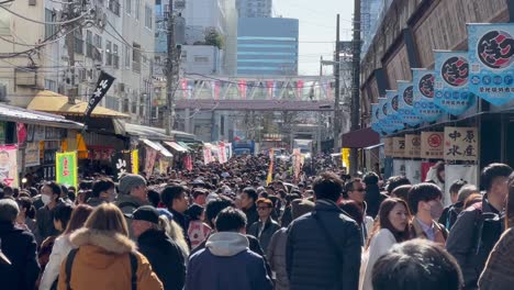 Crowds-walking-under-the-bridge-and-stores-of-the-Tsukiji-Fish-Market,-Tokyo-Japan
