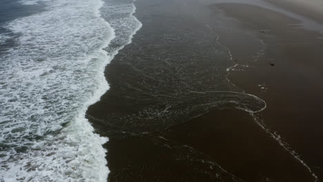 Waves-from-Pacific-Ocean-breaking-in-slow-motion-on-sandy-beach,-Oregon-Coast