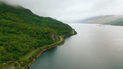 Aerial-shot-along-Scottish-sea-loch-coastline-with-winding-road