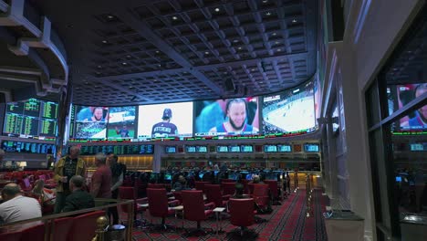 Panning-view-of-a-las-vegas-sports-book-with-a-group-of-men-conversing