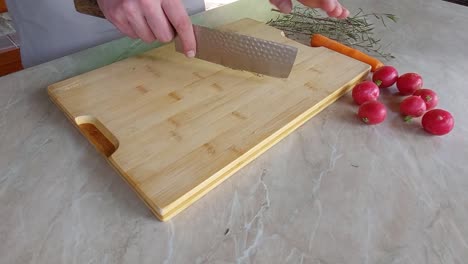 Cuting-Fresh-Rosemary-on-wooden-board-with-Japanese-ryukiri-nikiri-knife
