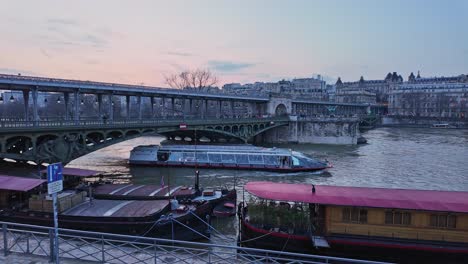 Boat-passing-under-Bir-Hakeim-bridge-crossing-Seine-river,-Paris-during-twilight,-France