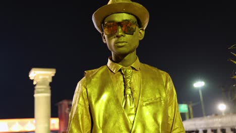 Artista-Callejero-Con-Traje-Dorado-Y-Sombrero-Con-Rosa-En-La-Calle-Por-La-Noche-Video-Tomado-En-Ram-Mandir-Y-Saryu-Ghat-Yodhya-Uttarpradesh-India-Mar-06-2024