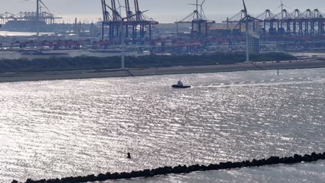 Tug-Boat-Sailing-In-Nieuwe-Waterweg-Along-The-Wind-Turbines-And-Industrial-Port-In-Hoek-van-Holland,-Netherlands