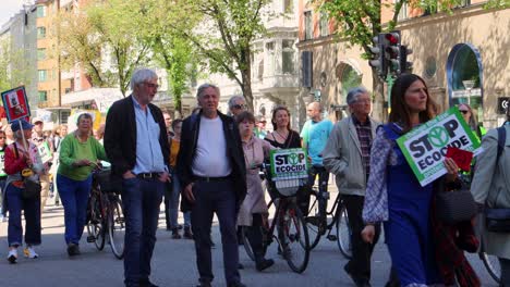 Manifestantes-Sosteniendo-Pancartas-Para-Detener-El-Ecocidio-Durante-Una-Marcha-De-Protesta-Por-El-Medio-Ambiente-En-Estocolmo,-Suecia,-Toma-Amplia