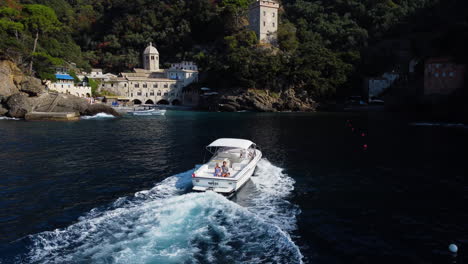 Aerial-view-following-a-motorboat-arriving-at-the-San-Fruttuoso-abbey,-in-Italy