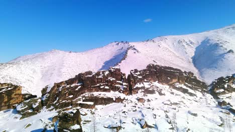 Parallax-of-rocks-against-the-backdrop-of-gray-mountains-and-blue-sky-from-a-4k-drone