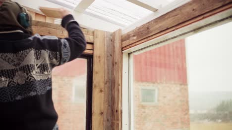 Man-Using-Cordless-Drill-To-Screw-Wooden-Planks-On-The-Greenhouse-Walls