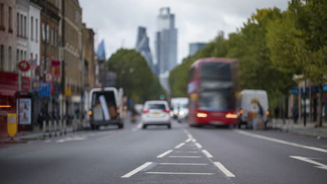 Lapso-De-Tiempo-Del-Tráfico-De-Las-Calles-De-Londres-Entrando-Y-Saliendo-De-La-Ciudad-Desenfocado-Usando-La-Profundidad-De-Campo-En-Primer-Plano-Con-Rascacielos-En-El-Fondo