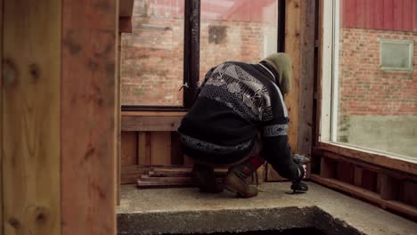 Man-Screwing-Wood-Planks-On-The-Walls-Of-Greenhouse-In-The-Farm