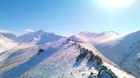 flying-at-bird's-eye-height-over-snowy-cliffs-in-sunny-weather-4k