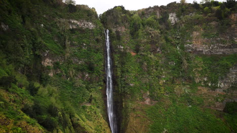Flying-towards-waterfall-in-green-mountains,-Rocha-do-Navio,-Madeira,-Portugal