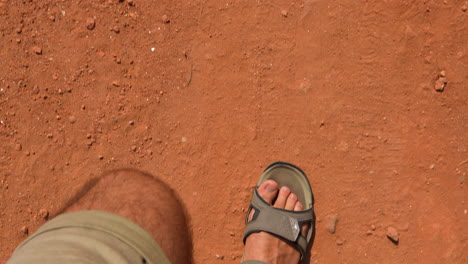 Legs-in-trekking-sandals-walking-on-a-sandy-path-in-desert
