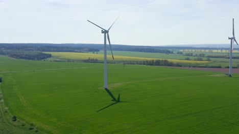 Aerial-view-wind-turbine-generates-green-energy-on-a-sunny-day,-blue-cloudy-sky