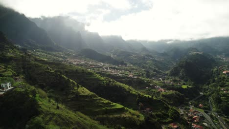 4k-Atemberaubende-Luftaufnahme-Der-Landschaft-Madeiras-Mit-Bergen,-Schluchten-Und-Dorf-An-Einem-Bewölkten-Tag