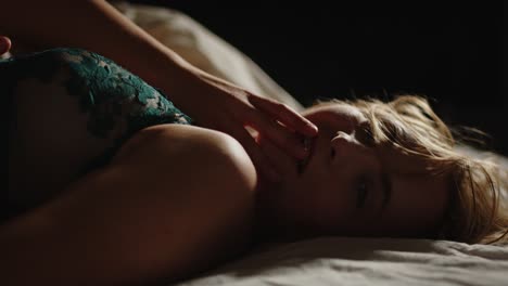 Close-up-of-an-enticing-woman-dressed-in-lingerie-sensually-looking-at-camera-while-laying-in-bed