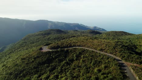 Aerial-of-Scenic-Green-Mountains-Road,-Ocean-View,-Landscape-at-Sunset