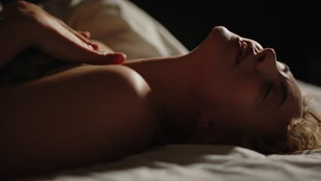 A-beautiful-woman-lays-in-bed-and-sensually-touches-her-face-in-pleasure-and-looks-at-the-camera