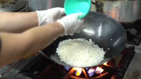 Close-up-of-Chef-hands-cooking-and-thowing-white-rice-for-Asian-cuisine-in-frying-wok-pan-on-gas-stove