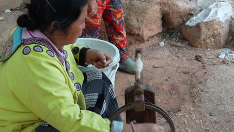 Asian-old-woman-manually-spinning-a-wooden-yarn-machine-in-slow-motion