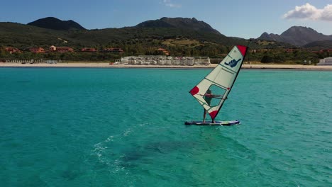 Drone-shot-passing-windsurfers,-sunny-summer-day-in-Costa-Smeralda,-Sardinia,-Italy