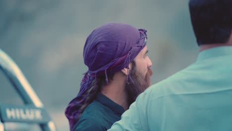 Side-view-of-long-bearded-man-talking-to-other-Pakistani-men-in-Iftar-Drive-of-Balochistan,-Pakistan