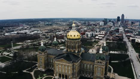 Drone-shot-of-the-Des-Moines,-Iowa-capitol-building-with-the-city's-downtown-skyscrapers-off-in-the-distance