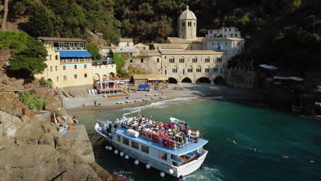 Aerial-view-of-a-tourist-tour-ferry-arriving-at-the-San-Fruttuoso-abbey,-in-Italy