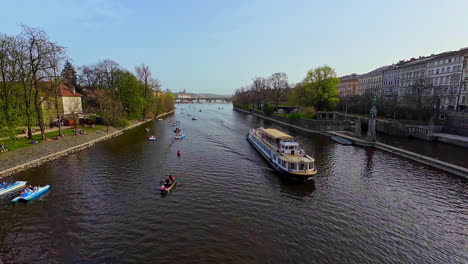 High-angle-shot-from-over-a-bridge-of-a-tourist-motor-boat-passing-by-in-Vltava-river,-Czech-Republic-on-a-sunny-day