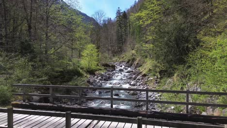 4K-Aerial-Drone-Flight-through-Mountain-Valley-with-Bridge-above-Idyllic-River-with-Crystal-Clear-Turquoise-Water-in-Europe