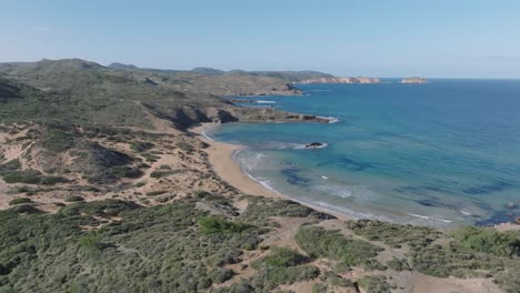 Aerial-landscape-of-dry-forested-turquoise-water-white-sand-beach-cavalleria,-north-of-Menorca,-Spain