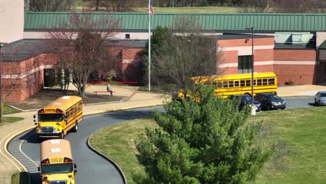 Aerial-view-showing-row-of-yellow-school-buses-leaving-parking-area-of-school