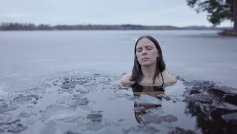 Ice-bathing-woman-in-a-glassy-still-lake-tilts-her-head-back-slightly,-dusk