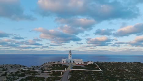 Wide-angle-blue-day-skyline-drone-above-Cavalleria-lighthouse-Menorca-sea-fields-horizon-ocean-background,-clifftop-island