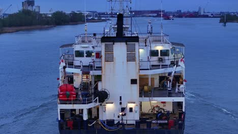 Rückseite-Eines-Stückgutschiffs,-Das-In-Der-Abenddämmerung-Auf-Dem-Fluss-In-Zwijndrecht,-Niederlande,-Segelt