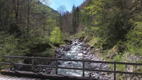 4K-Drohnenflug-über-Einer-Brücke-Durch-Ein-Gebirgstal-Mit-Einem-Idyllischen-Fluss-Mit-Kristallklarem,-Türkisfarbenem-Wasser-In-Europa