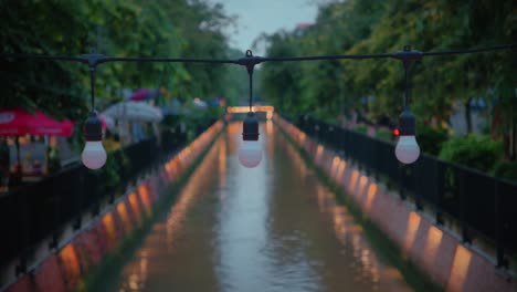 Toma-De-Foco-En-Bombillas-Con-Vista-Borrosa-Del-Canal-Khlong-Ong-Ang-Al-Fondo-En-Bangkok