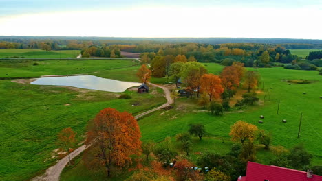 Autumn-colors-in-remote-country-home-with-big-pond,-aerial-drone-view